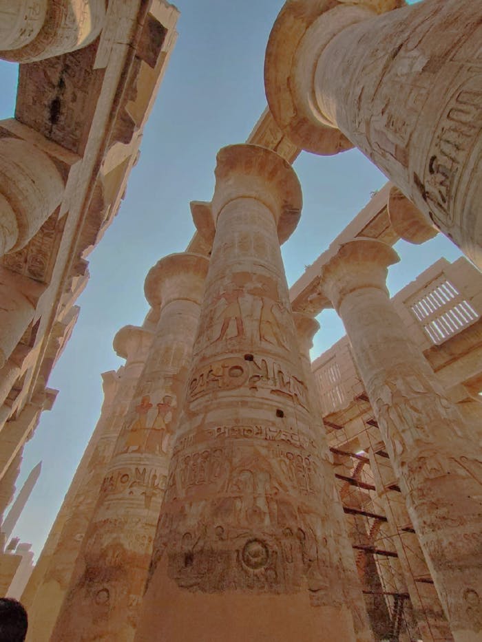 Low angle view of Karnak Temple pillars in Luxor, showcasing ancient Egyptian architecture and hieroglyphs.